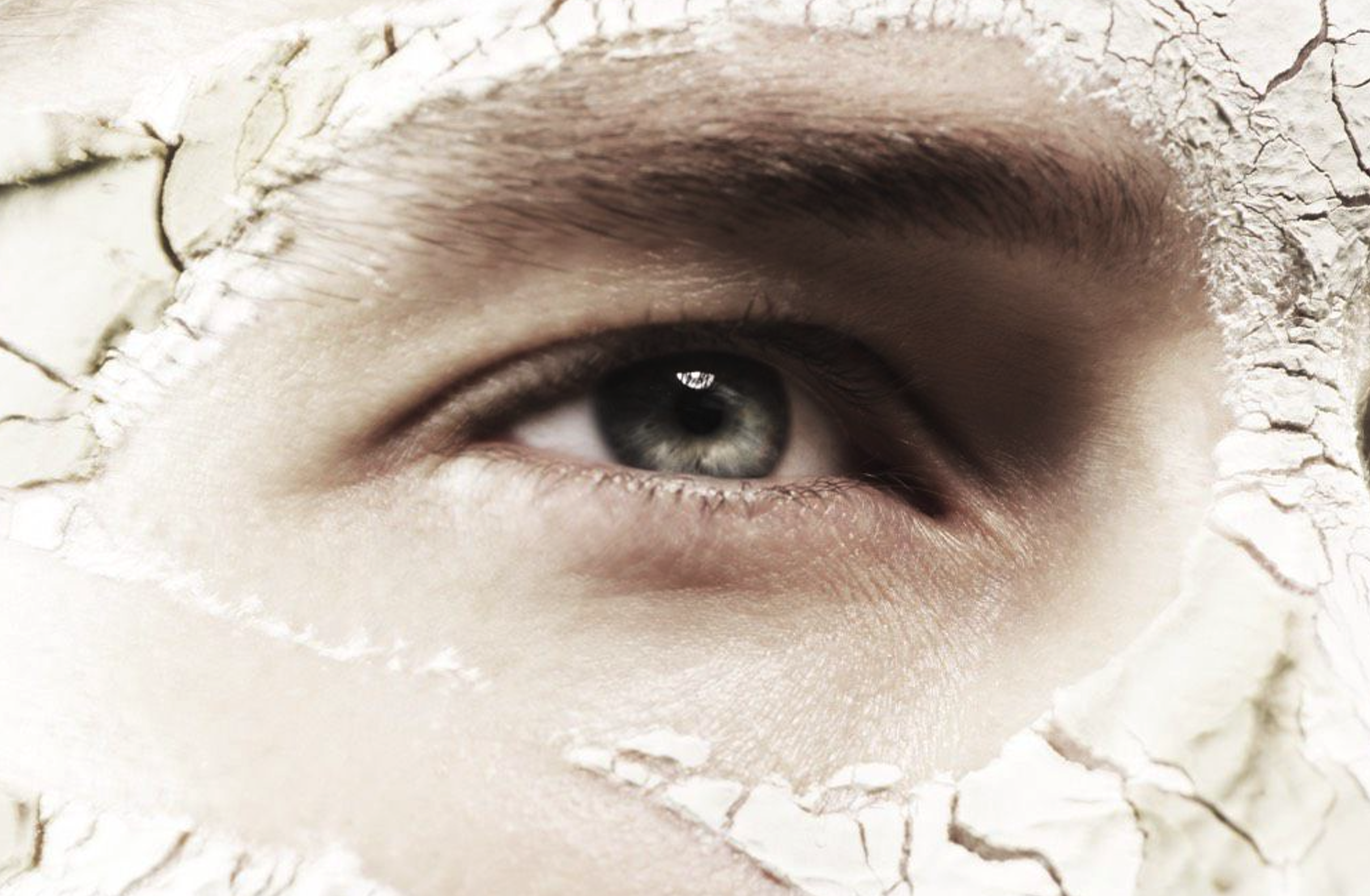 Close-up of a person's eye, partially covered by torn white paper with a rough texture.