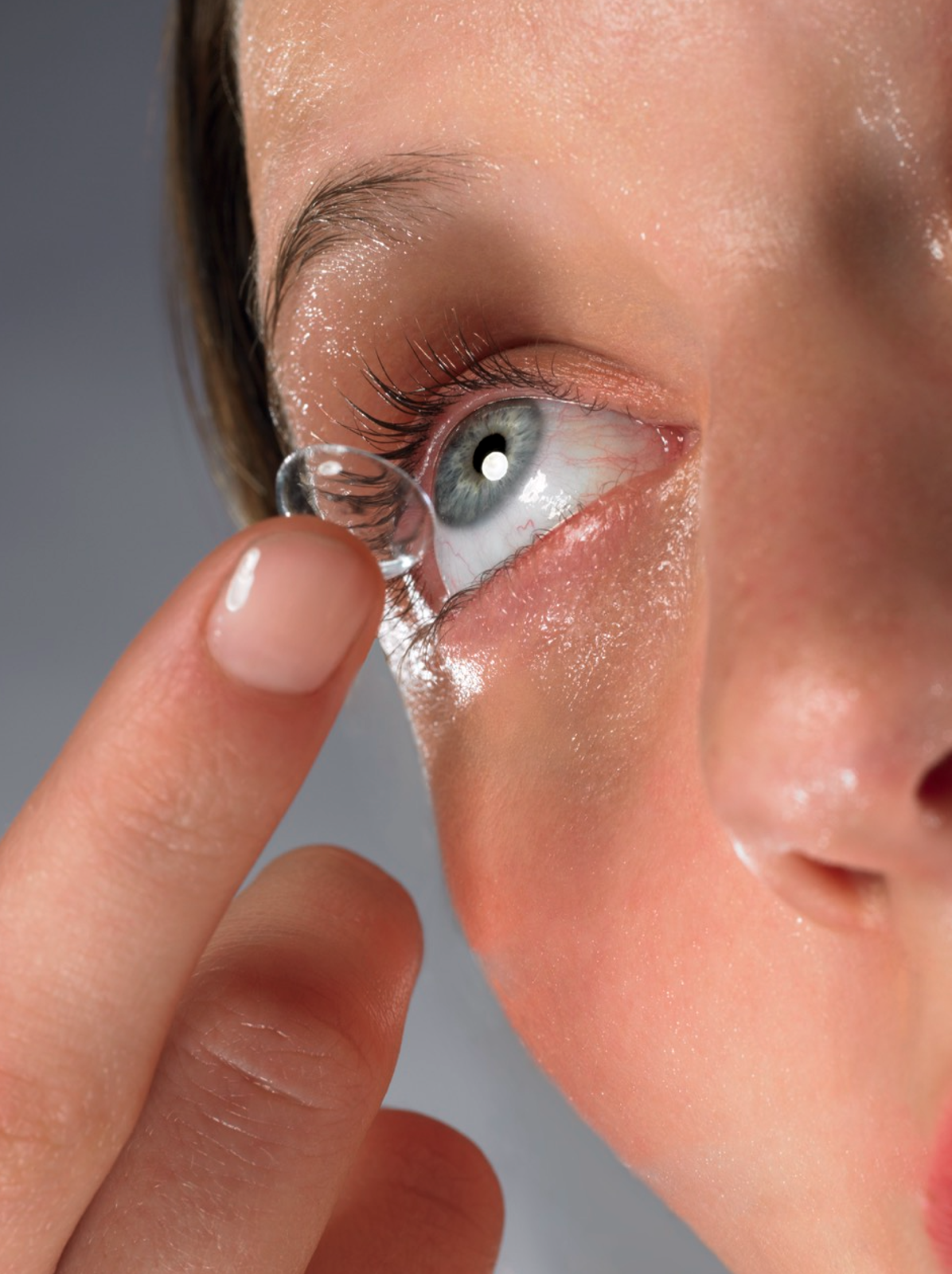Close-up of a person inserting a contact lens into their eye.