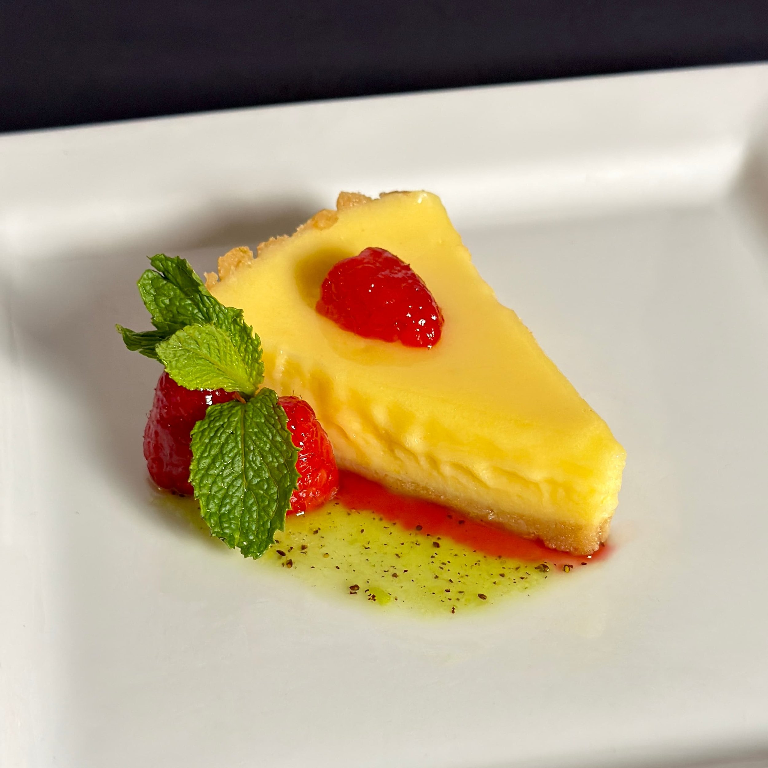 A slice of scratch made highly reviewed key lime pie with kiwifruit syrup and glazed raspberries.