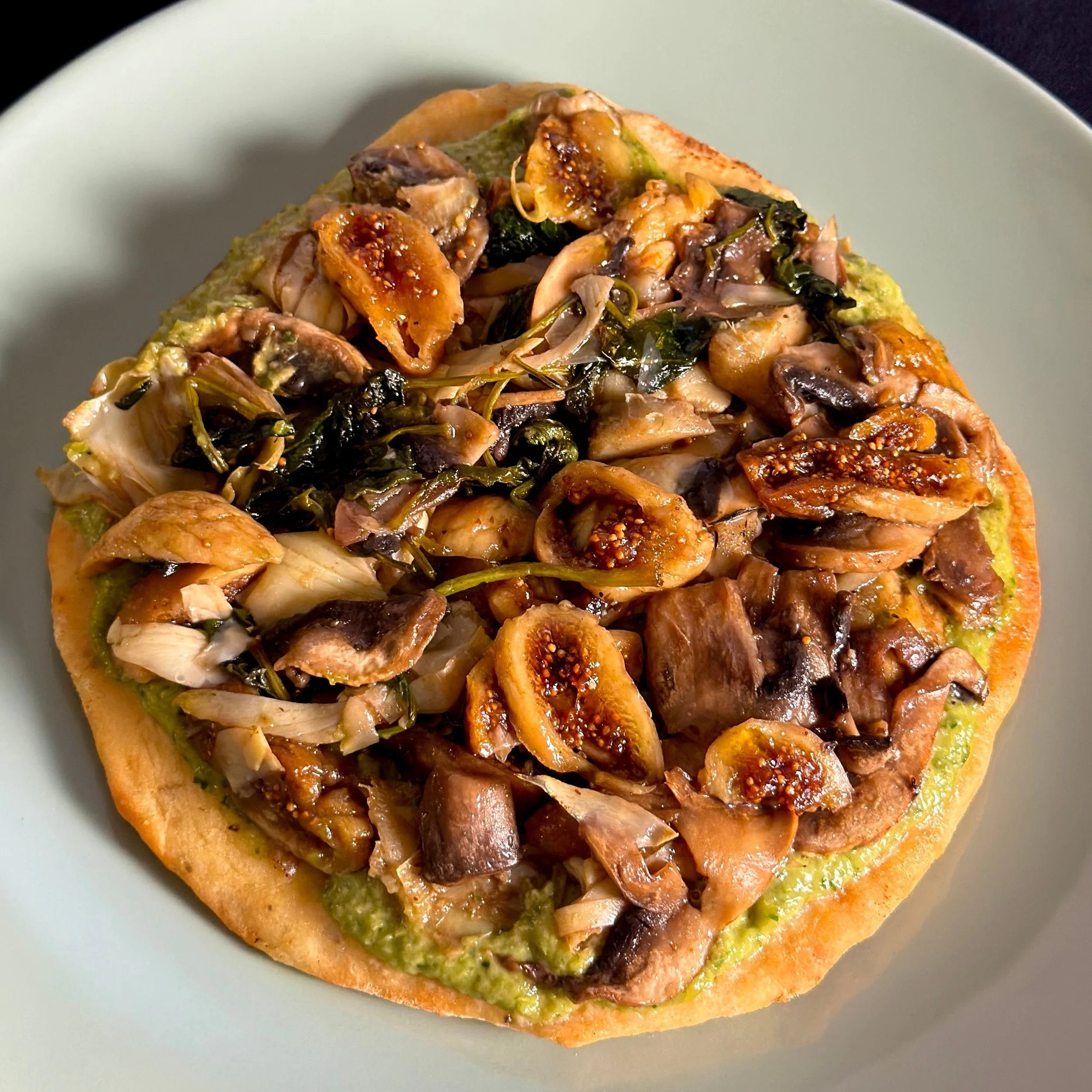 Fine dining upscale vegetarian oaxaca flatbread with black fig, cremini, artichoke, and basil.