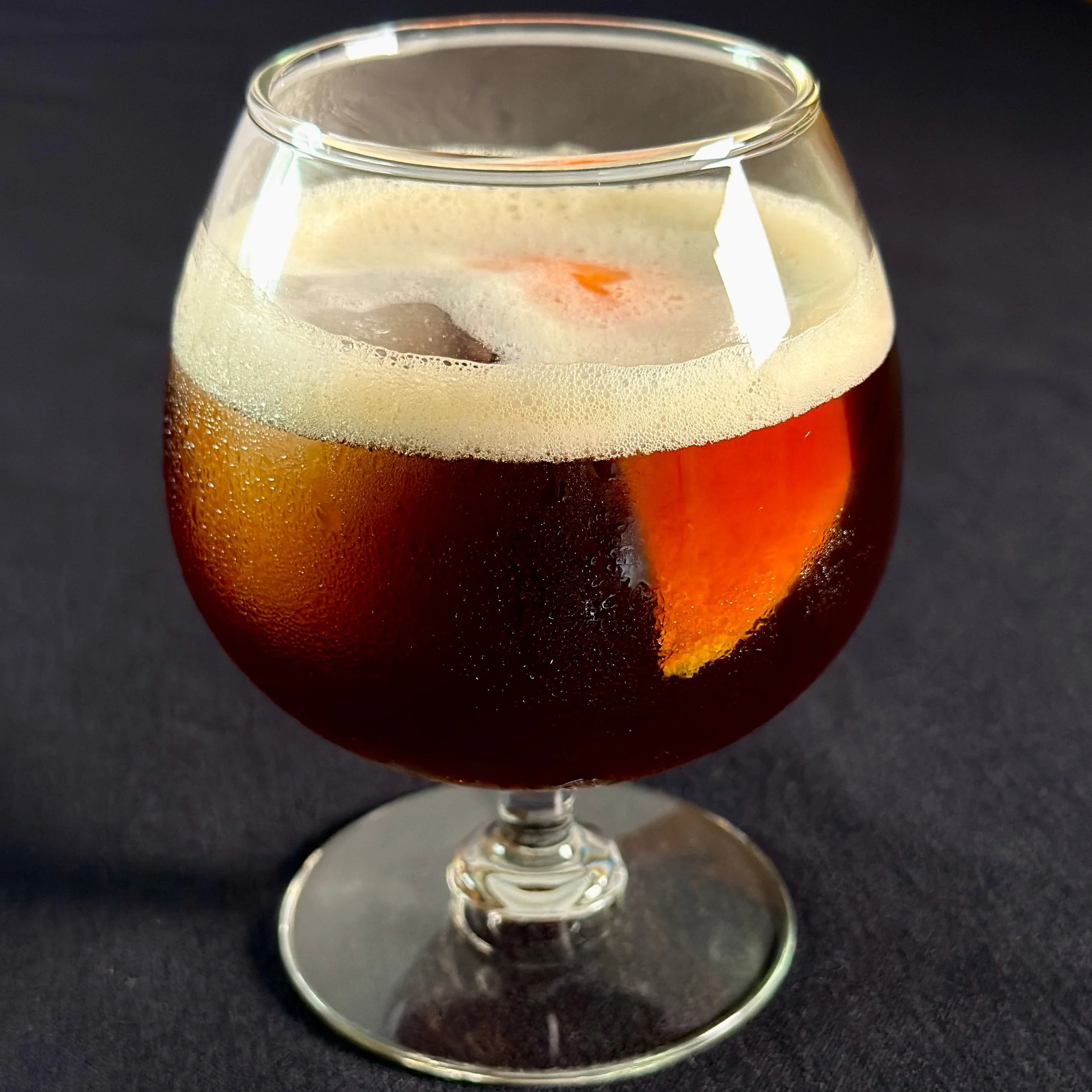 Black Bear Bistro's signature carajillo cocktail which is made with rum, licor 43, espresso, and a secret ingredient. Garnished with an orange slice.