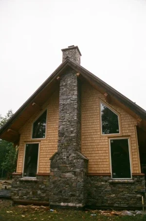 A tall stone chimney with a wide base in an A frame house