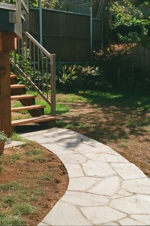 A curved flagstone pathway made of slate, leading to a side entrance stairway