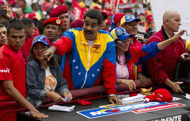 Venezuela's President Nicolas Maduro (C) greets supporters during a May Day rally in Caracas May 1, 2013. Opposition and government supporters flooded Venezuelan streets in rival May Day marches on Wednesday as a continuing dispute over the results of last month's presidential vote kept political tensions high in the OPEC nation. On Tuesday, opposition deputies were beaten in a fracas in Congress resulting from their refusal to recognize the presidency of Nicolas Maduro, who narrowly won the April 14 election triggered by the death of socialist leader Hugo Chavez. REUTERS/Carlos Garcia Rawlins (VENEZUELA - Tags: POLITICS) - RTXZ6SD