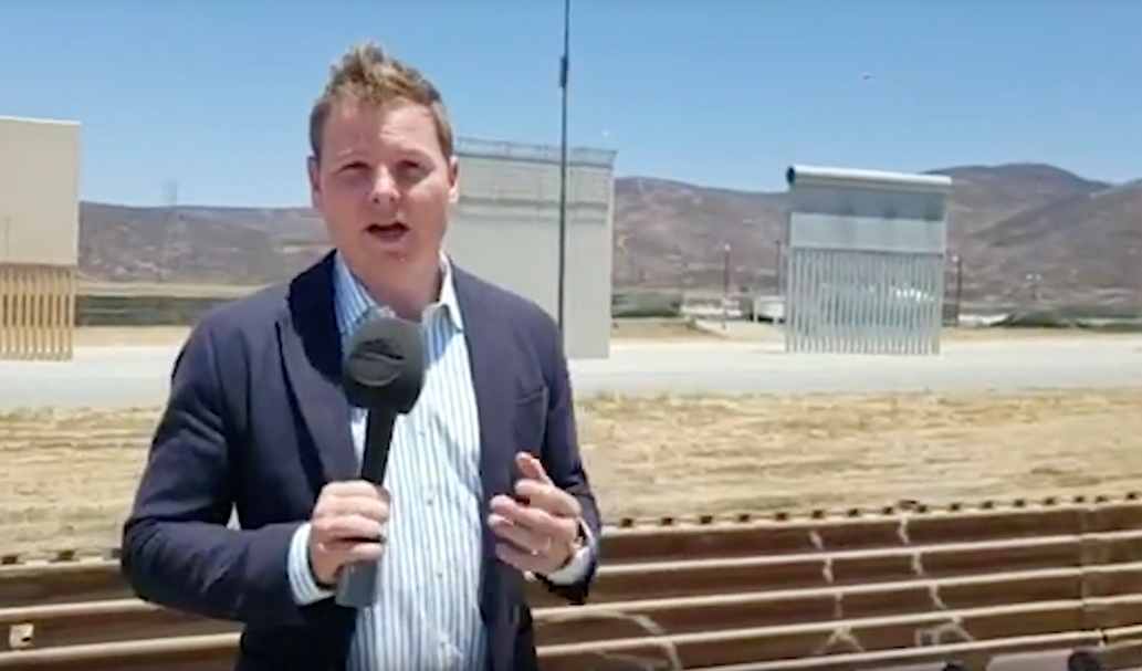 CGTN reporter Alasdair Baverstock stands on top of a Jeep to get a better angle of Donald Trump's border wall prototypes at the U.S.-Mexico border, May 5, 2018 /CGTN Photo
