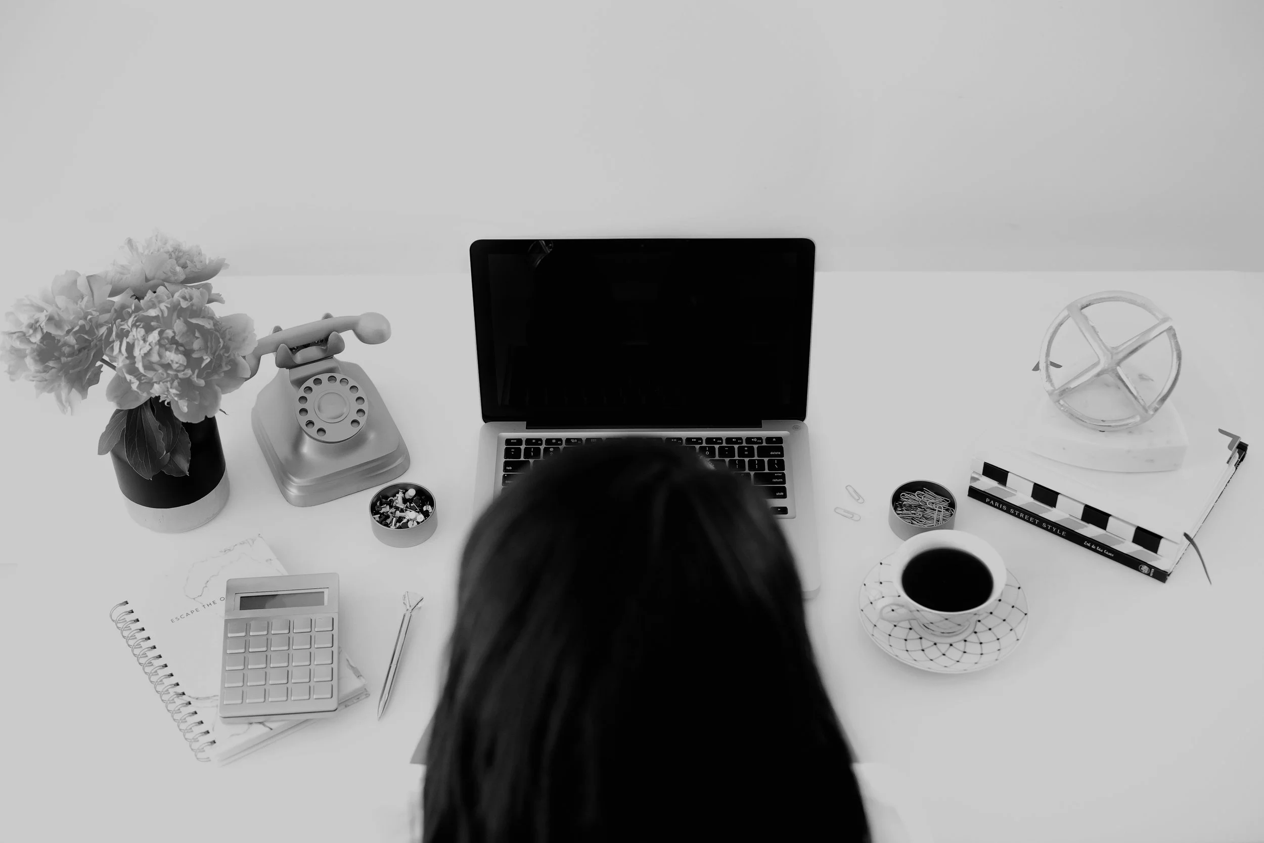 A black and white image of Serena Hicks at work on her laptop prepping for coaching calls