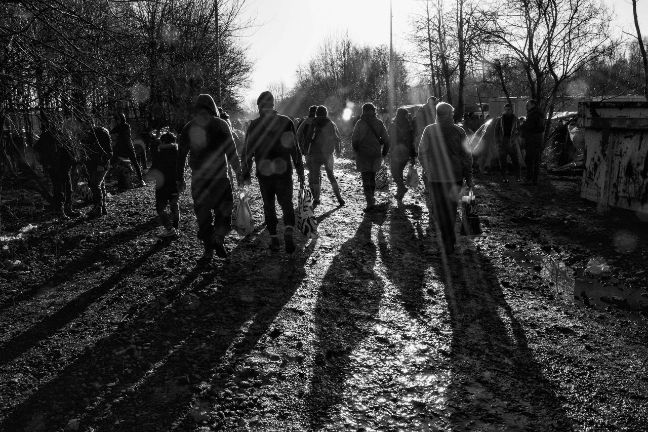  Asylum seekers carry on bags with food at the refugee camp of Grande-Synthe, Dunkirki, France, January 8, 2016. Photo Delmi Alvarez. 