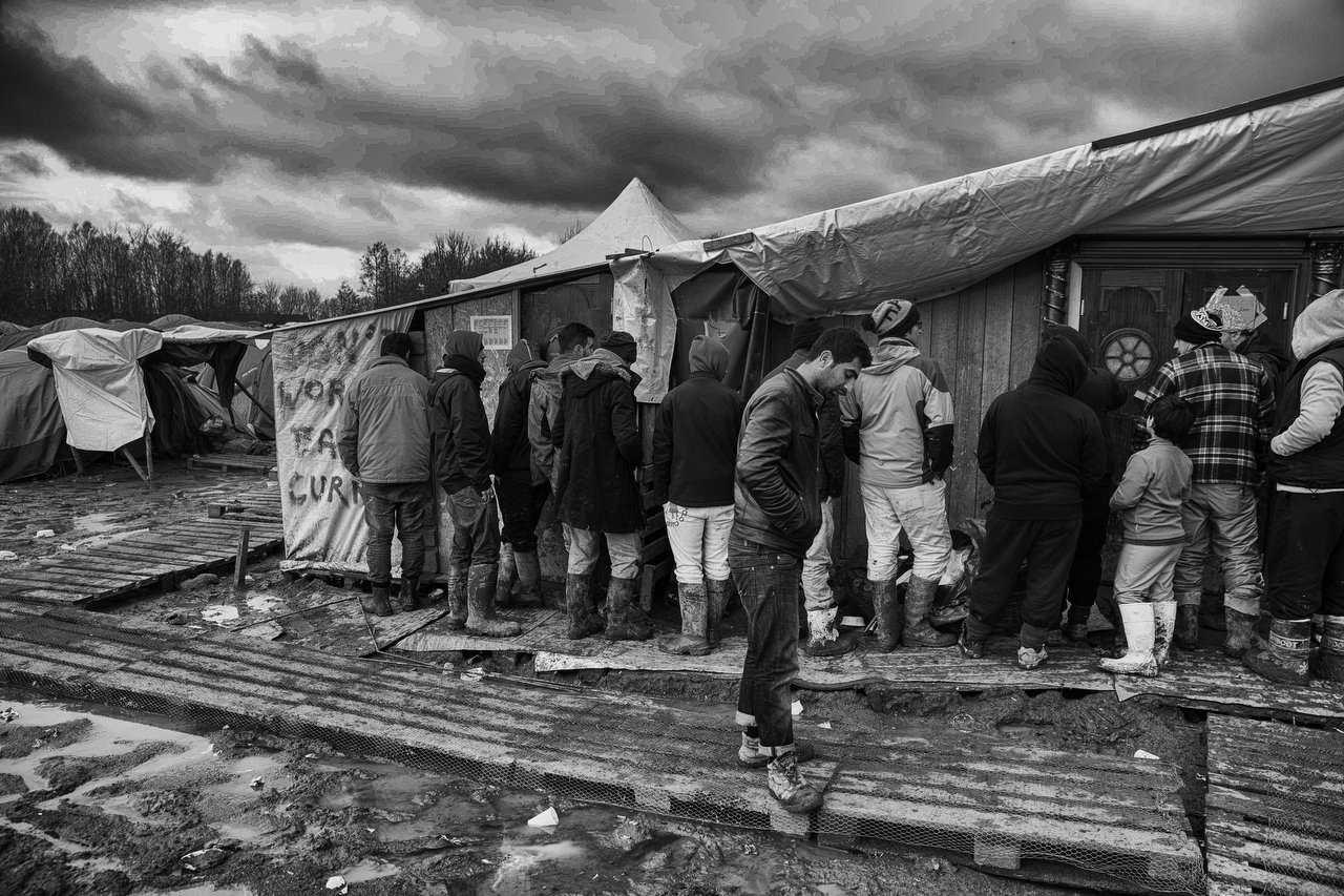  Migrants wait for clothes and shoes in a queue in a makeshift tent at camp of Grande-Synthe, Dunkirque, France, January 15, 2016. Photo Delmi Alvarez. 