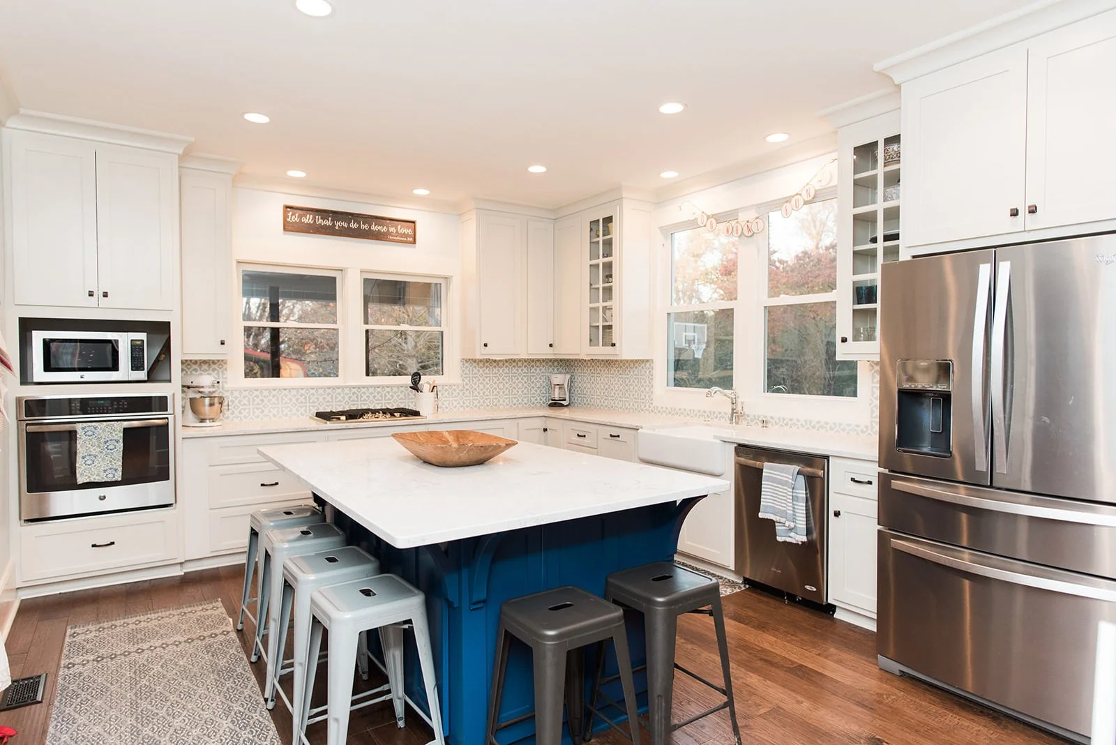 photo of updated kitchen with white cabinets and blue island and blue and white tile backsplash