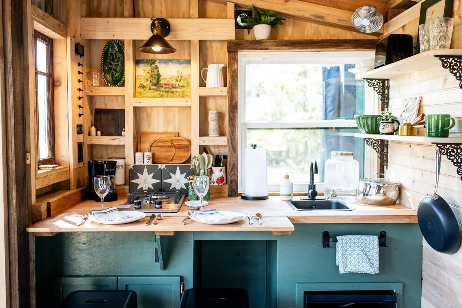 cute little custom kitchen with green cabinets and open shelving in an off-grid cabin