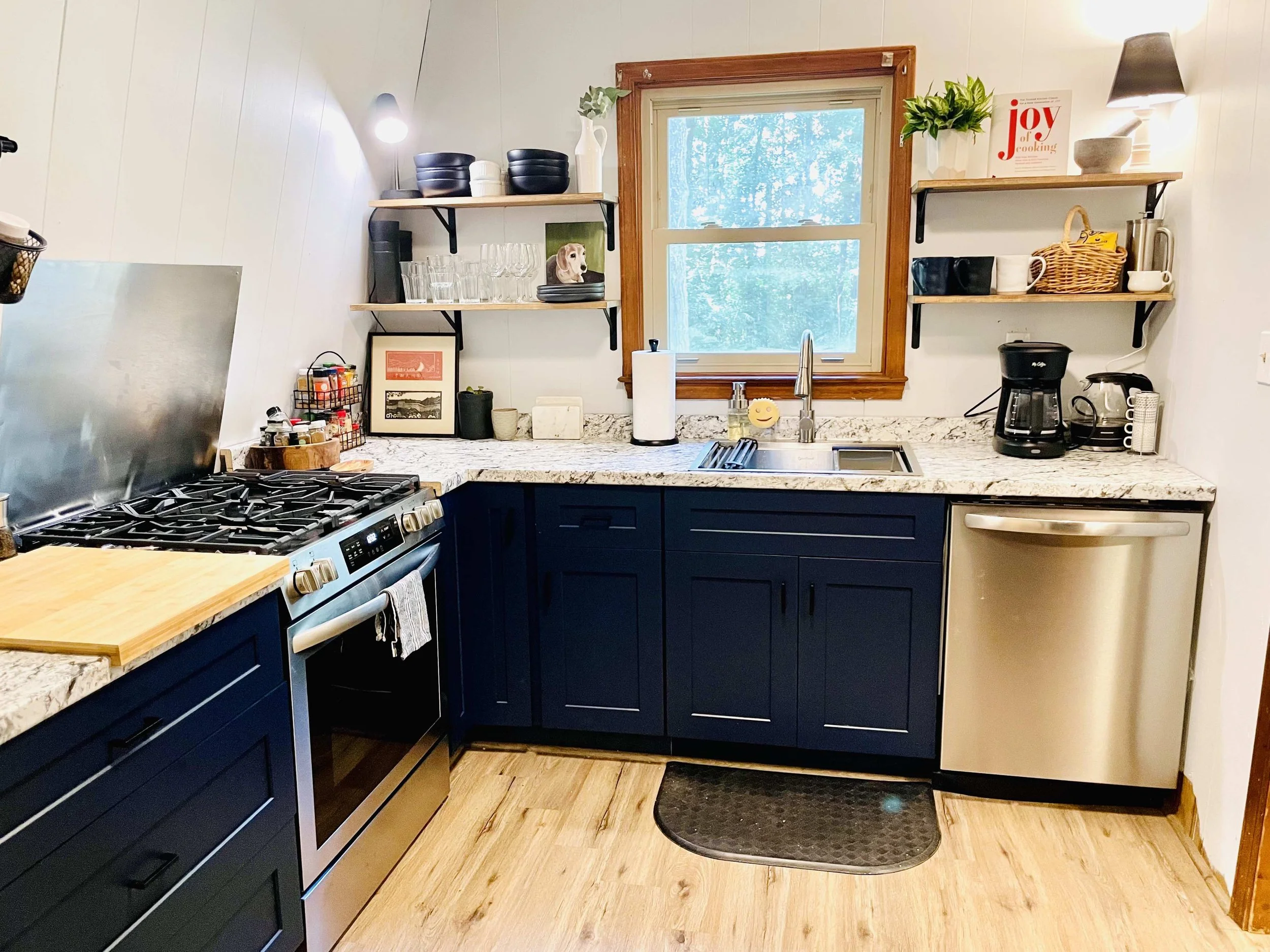 Kitchen in A-frame after being updated- blue cabinets, white walls. Looks better and bigger