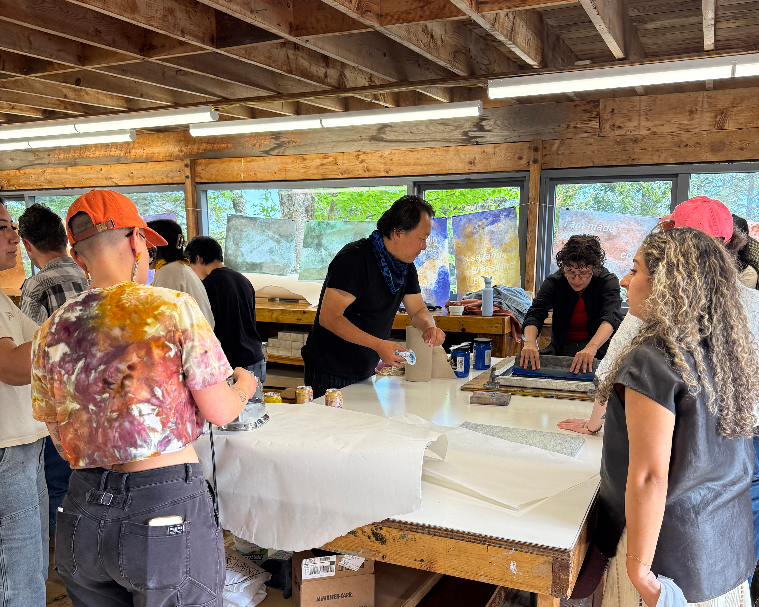 2026 Haystack Open Studio Residency_Image of several people standing around woo table waching individual screenprinting.png