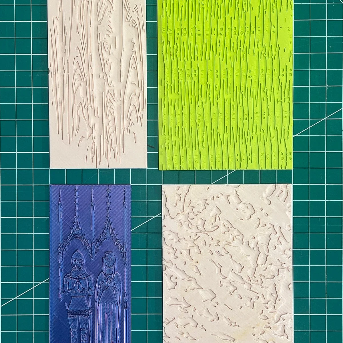 Image of four colorful, flat plastic molds with different textures
