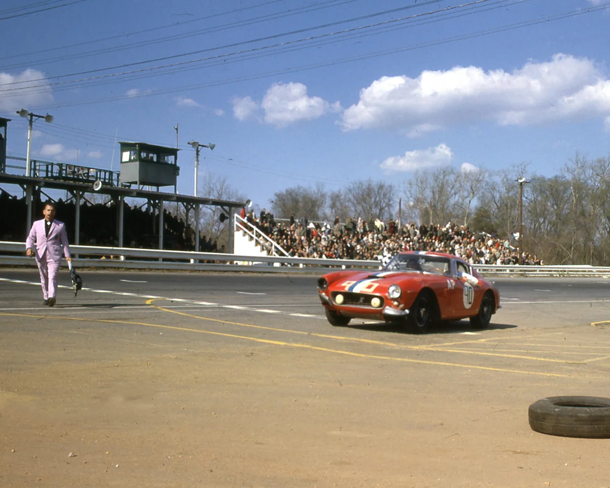 Tex Hopkins, the Lavender Hill Mob starter, brings the checkered flag to Bob Grossmans slightly battered Berlinetta.