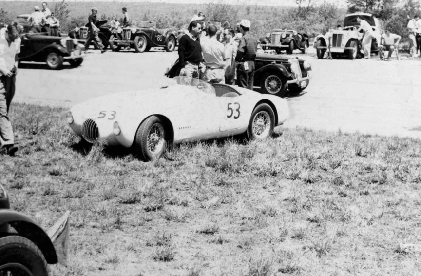 M. Weinman's White #53 OSCA sits in the grass with a gaggle of MG's behind.