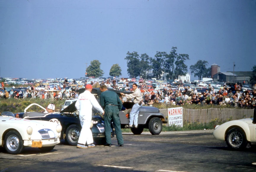 Dave Nicholas rides on John Kelley’s Jeep as they totally disrupt the start of the Collier Cup race. 17 year olds hiding in plain sight.