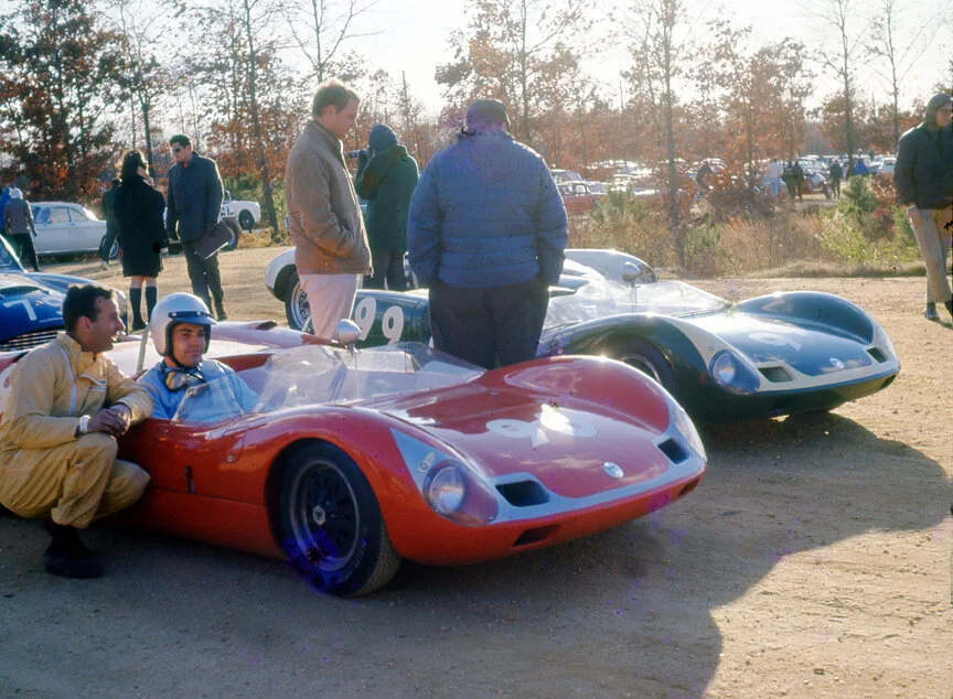 Skip Scott’s #96 Elva Mk VII and Peter Goetz’s similar car, #99, wait to be escorted to the start line. Scott would finish 2nd in the morning race and 3rd in the late race. Goetz did not start in the morning and would dnf in the afternoon race