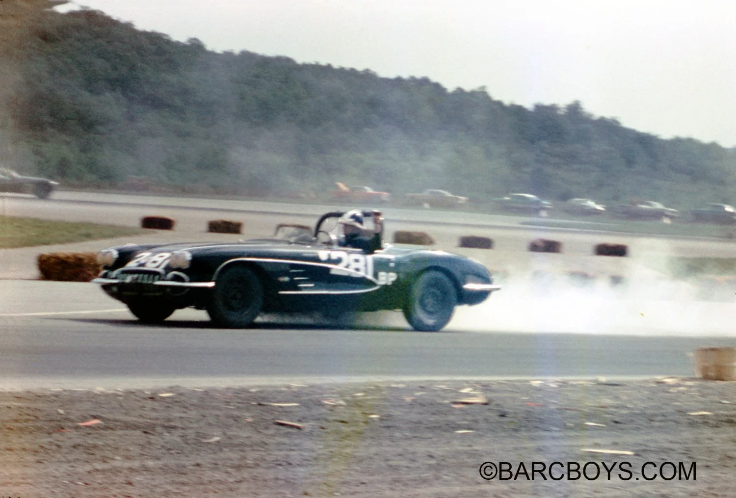  Alvin Forsythe holds his arm up to indicate he is heading into the pits in his wounded Vette.  From looking at the body we suspect the motor has gone. 