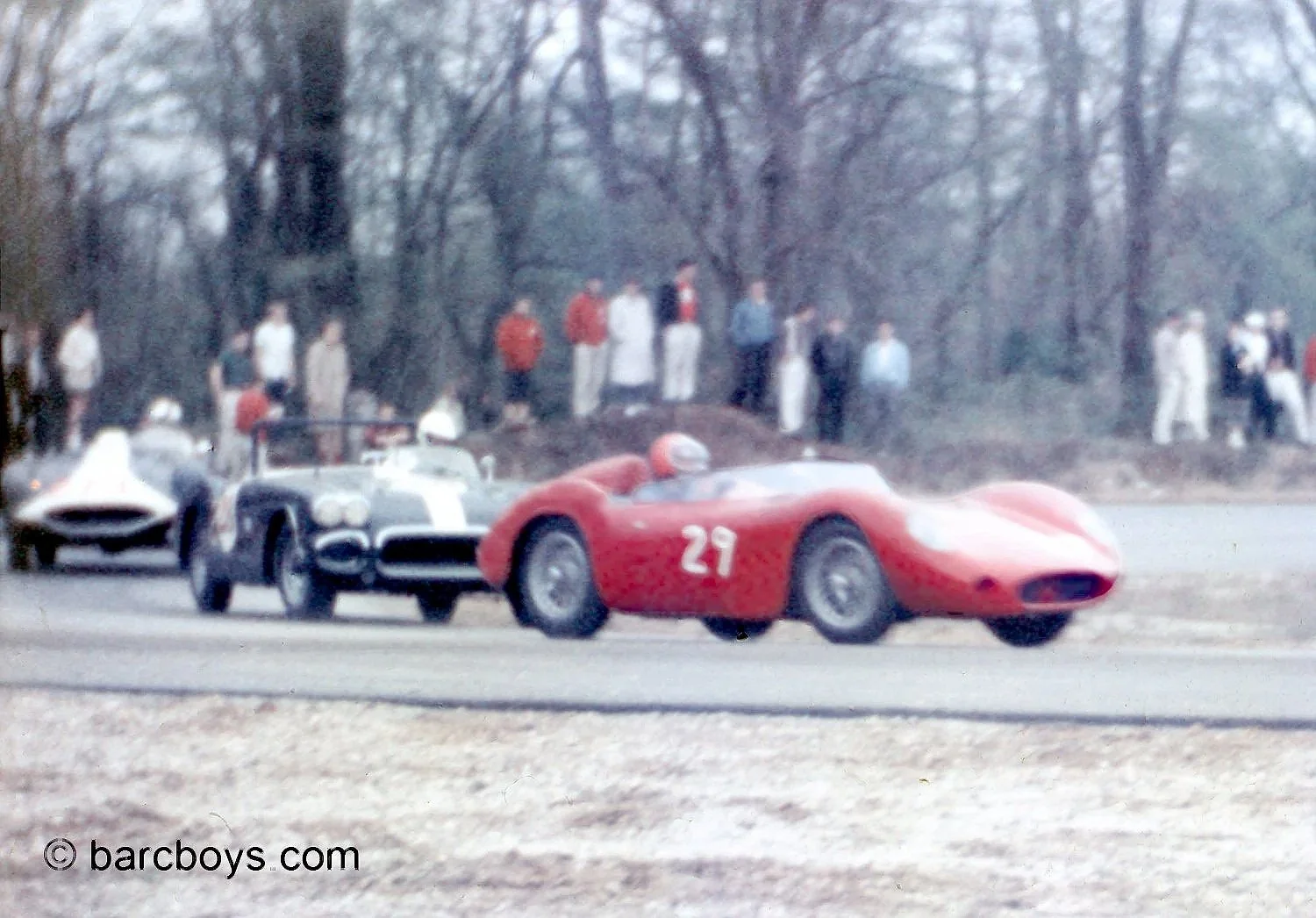  Traffic at the end of the short straight with Kolb’s Maserati leading  the Chevy engined specials of Bud Gates and Ray Hixon.  Being in early April the weather was chilly in southern Maryland.  The trees have barely budded and spectators are dressed