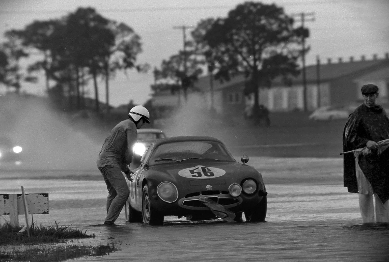  1965:  The rains were epic.  You can see this Alfa driver is ankle deep while standing on the track !  The current in the pits was so strong it literally floated spare wheels and tires away.  Somehow all the MGB’s continued to run despite Lucas elec