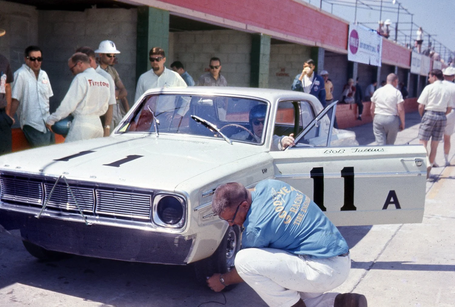  1966:  The very first TransAm is held as the 4 hr race at Sebring.  A Goodyeartech checks tires during practice.  Bob Tullius is in the car as Co Driver Tony Adamowicz (white shirt sunglasses) looks on.  They would finish 2nd overall to Rindt’s Alfa