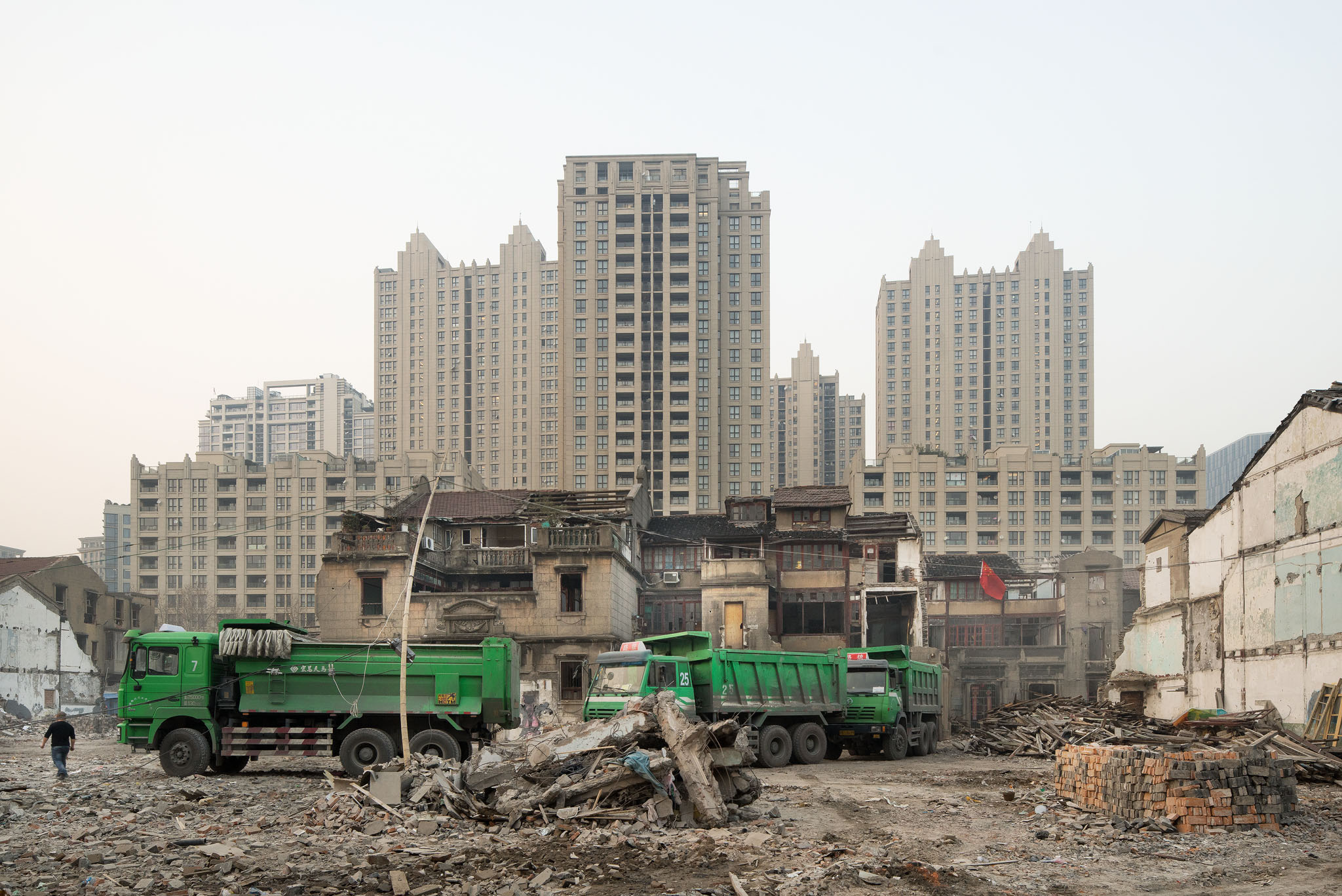 Demolition vehicles appear in the late afternoon, ready to start work as soon as darkness falls. The Chinese flag is flown as a symbol of resistance to the forced eviction.