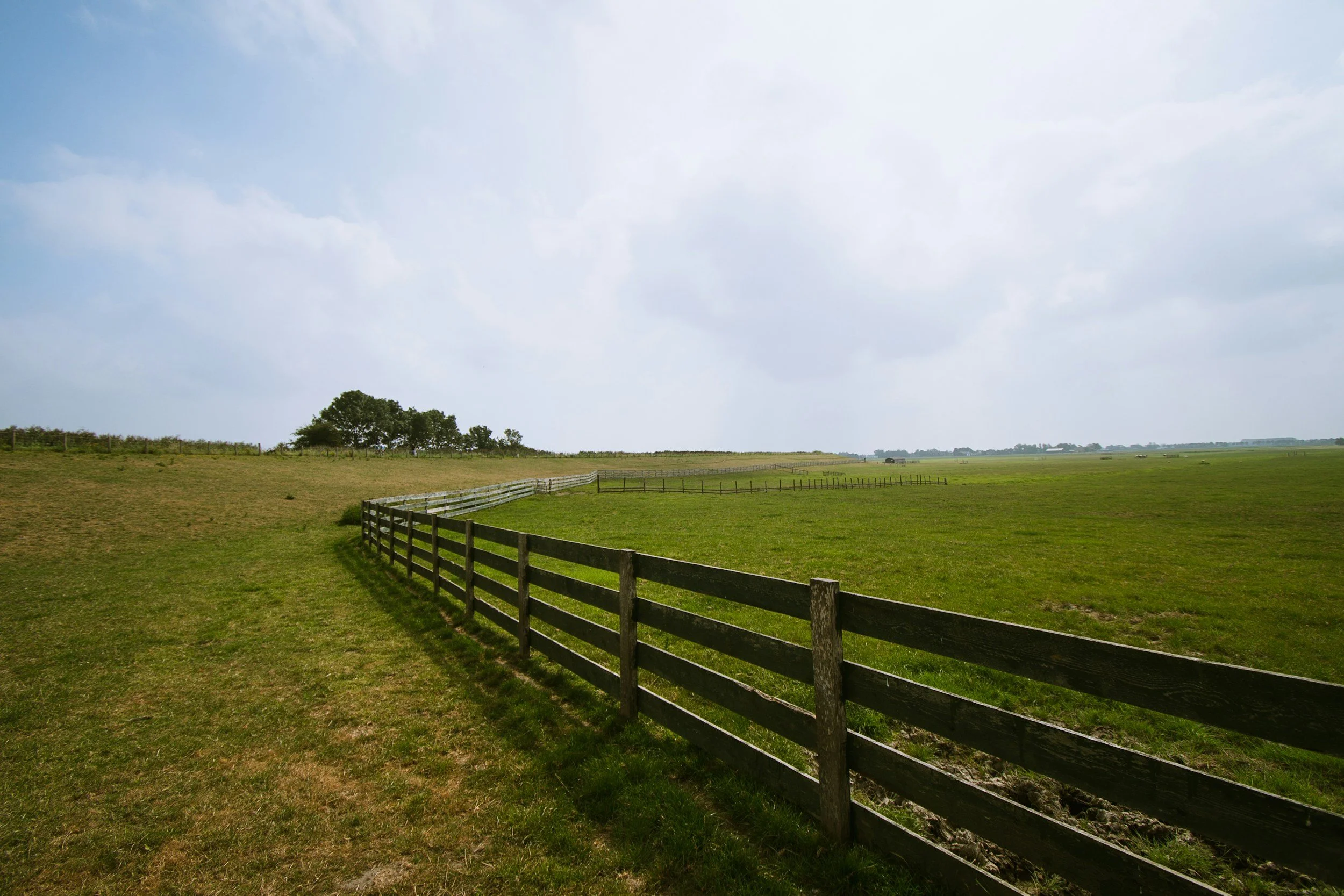 Wooden split-rail fence creating a clear boundary across a lush green pasture, symbolizing healthy relationship boundaries.