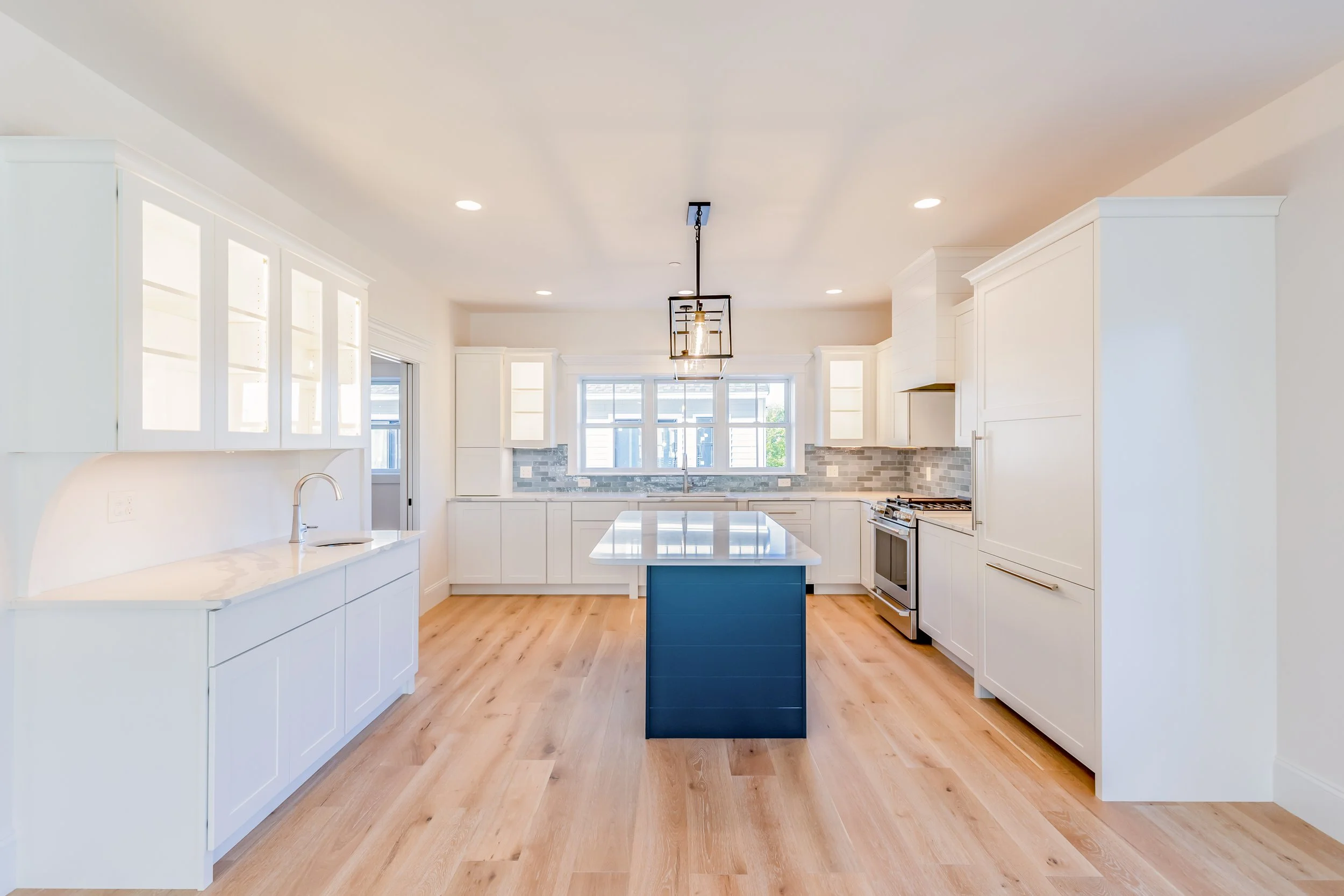 Bright white kitchen with long sightlines and recessed lighting creating visual depth