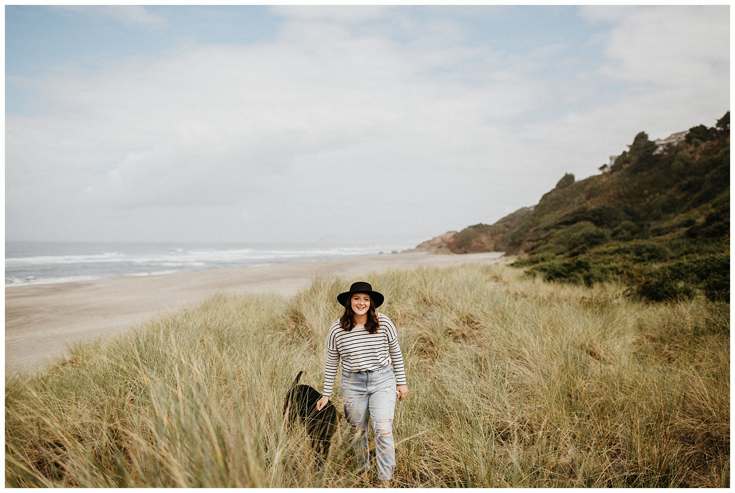  Girl looking at camera and smiling with her dog on the beach. 