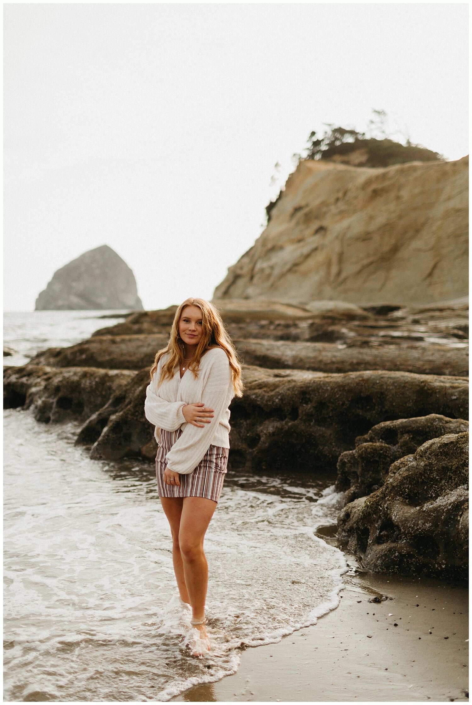  High school senior girl wearing a sweater at the beach in Oregon. 