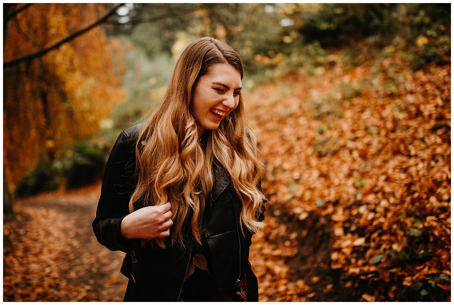  Girl laughing while surrounded by orange autumn leaves. 
