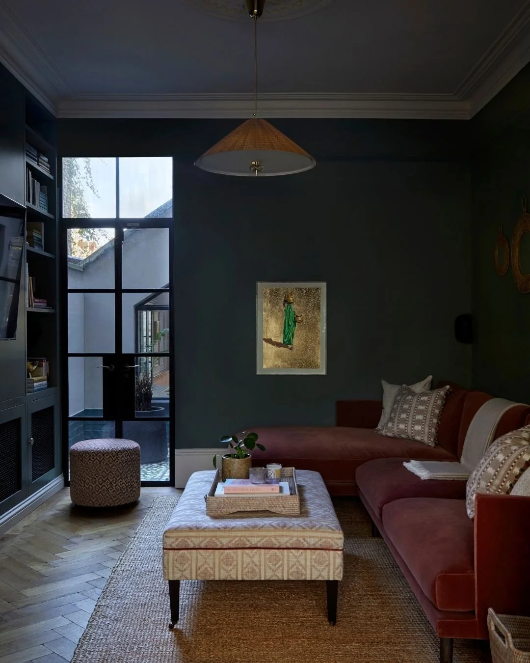 Dark and atmospheric living room at Chevening Road by Margot Tsim Interiors, with deep blue walls, rust velvet sofa and layered natural textures.