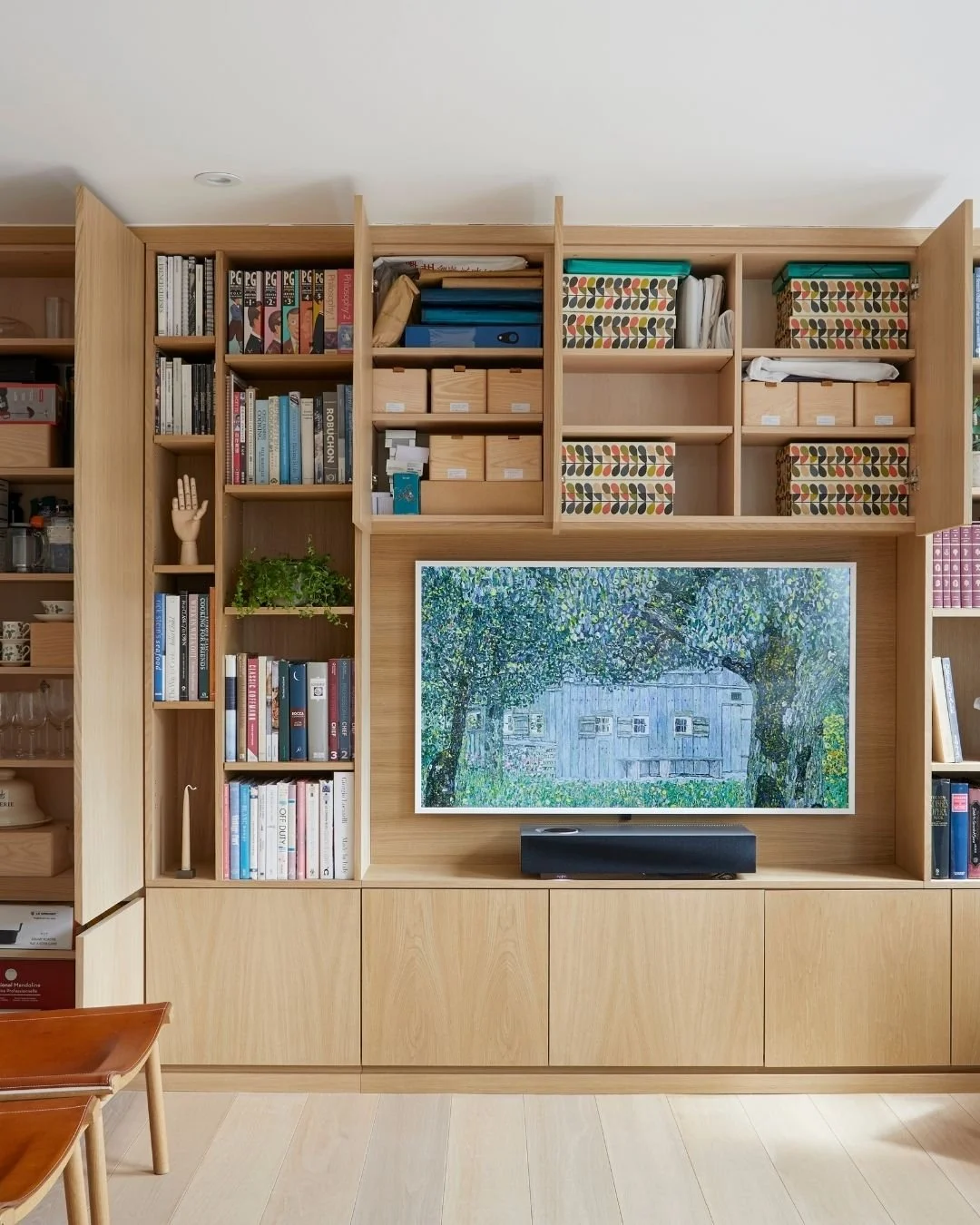 Bespoke oak media wall and storage at Elverton House by Margot Tsim Interiors, with integrated shelving, concealed cupboards and television.