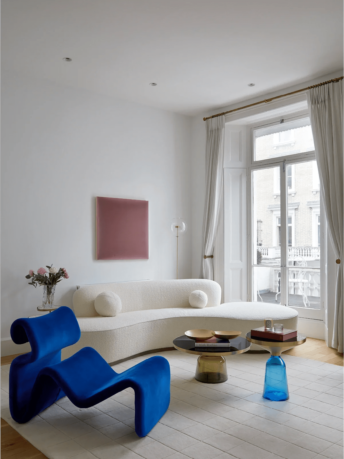 Elegant Mayfair apartment living room with large sash windows, sculptural furniture, rich colour accents and a curated collection of contemporary artwork in a luxury London interior.