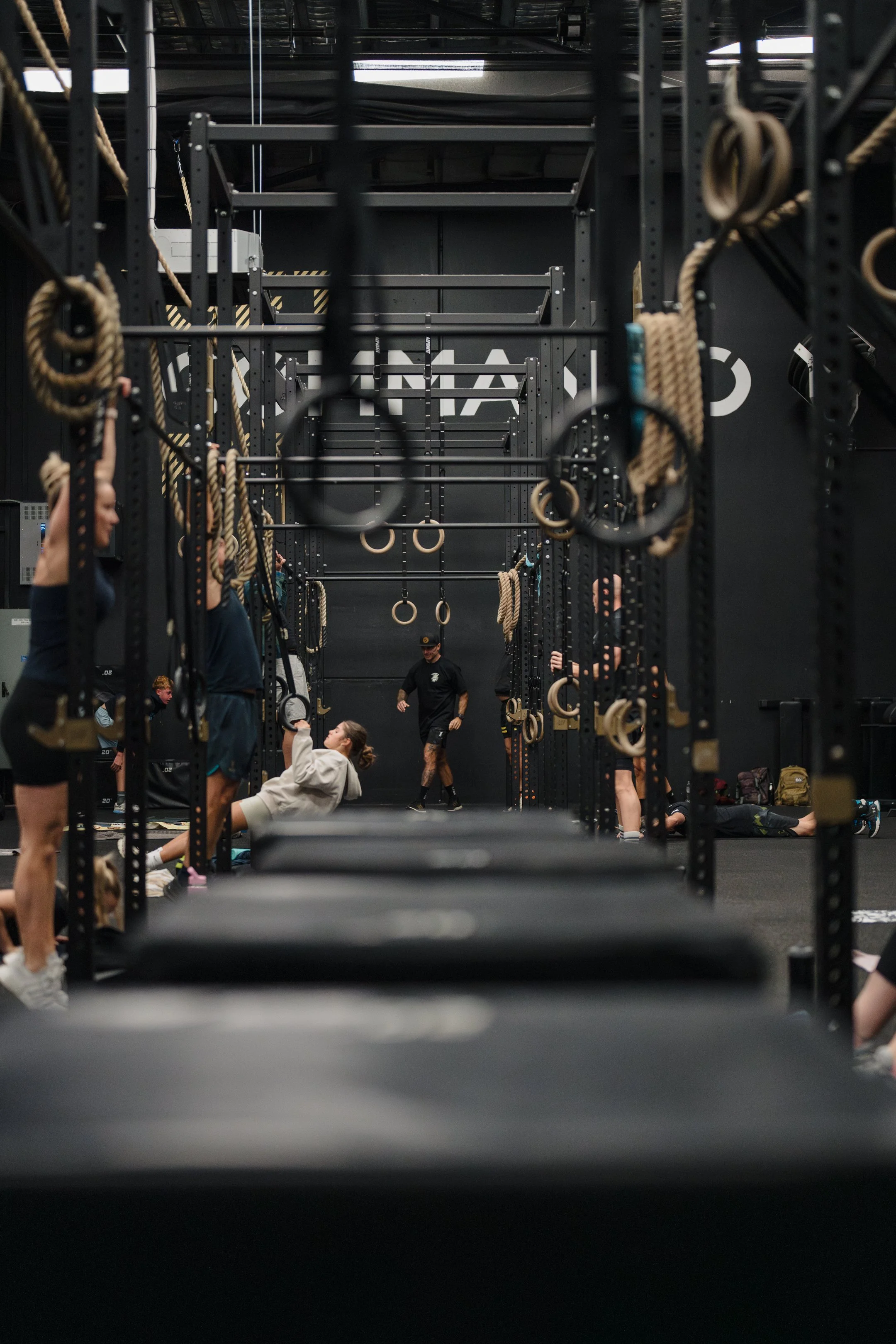 People working out in a gym with kettlebells, ropes, and padded platforms