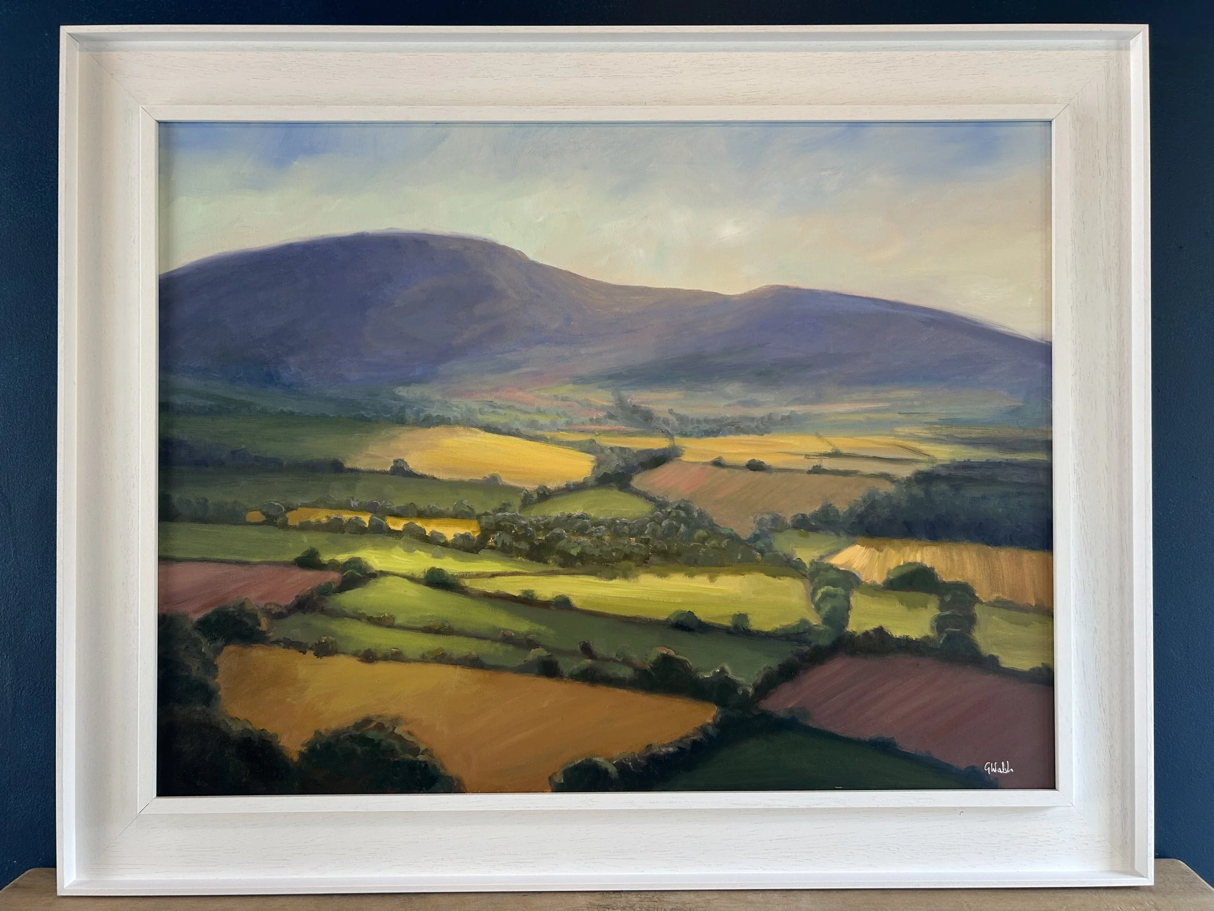 Landscape oil painting of the Blackstairs Mountains in Ireland under a soft, clouded sky with golden fields in the foreground.