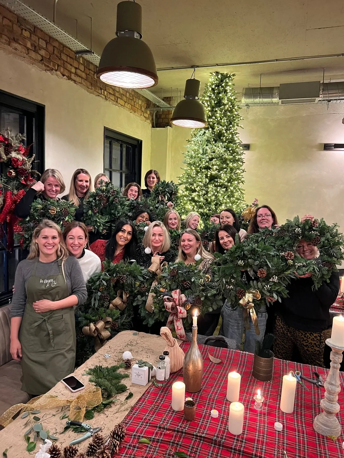 A large group holding their finished wreaths with Alex