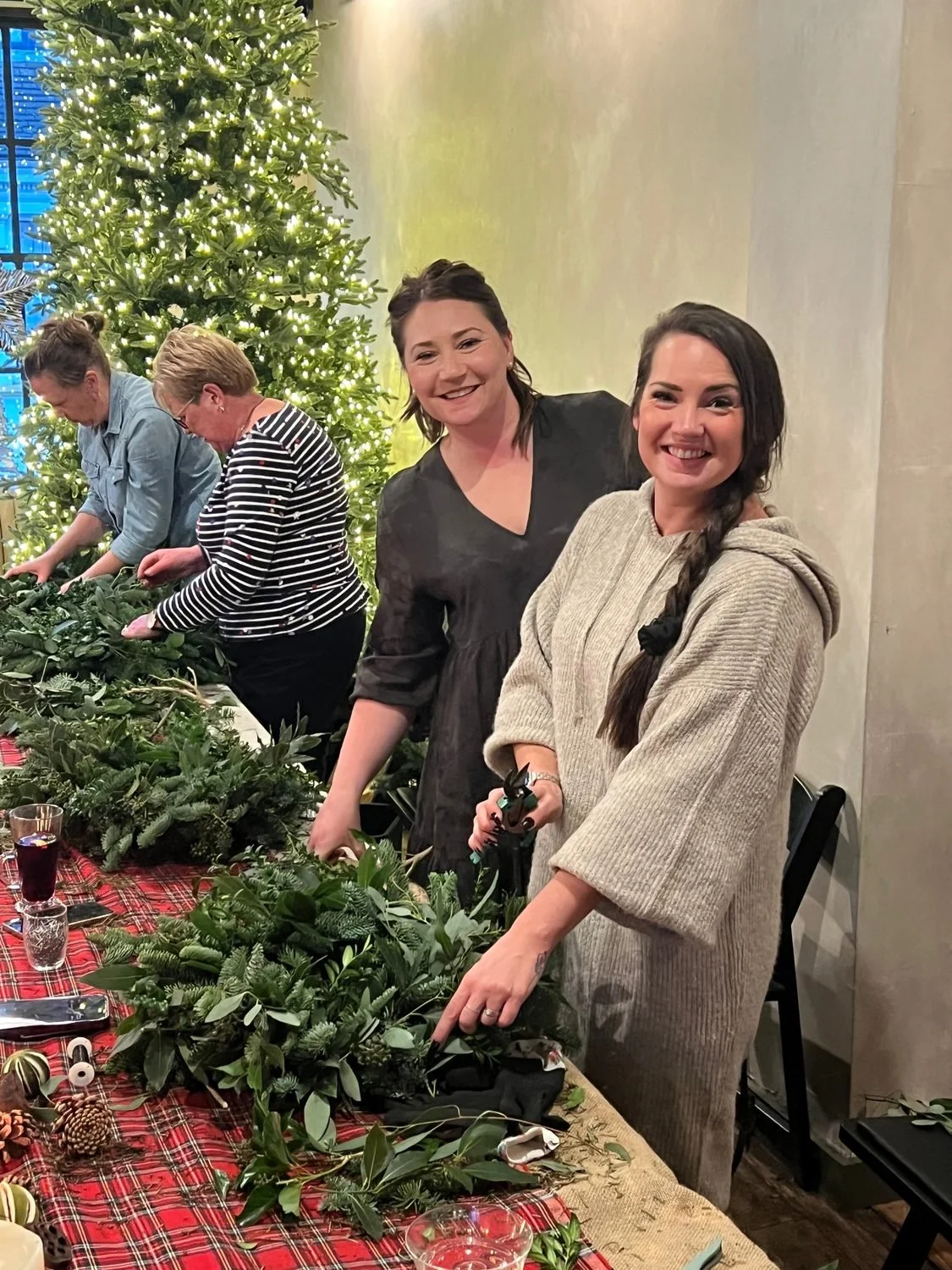 A small group of guests making wreaths around a table