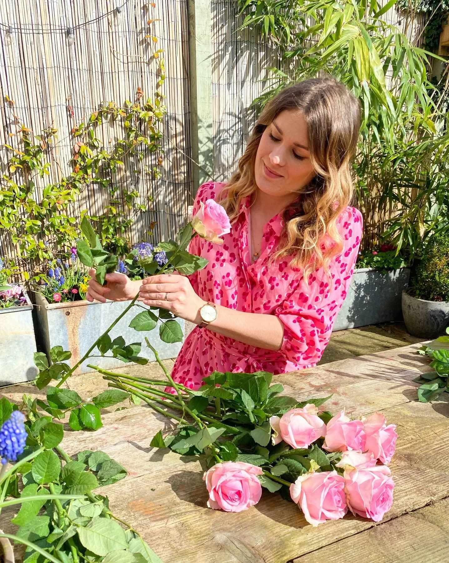 Alex arranging pink roses at a table in the garden