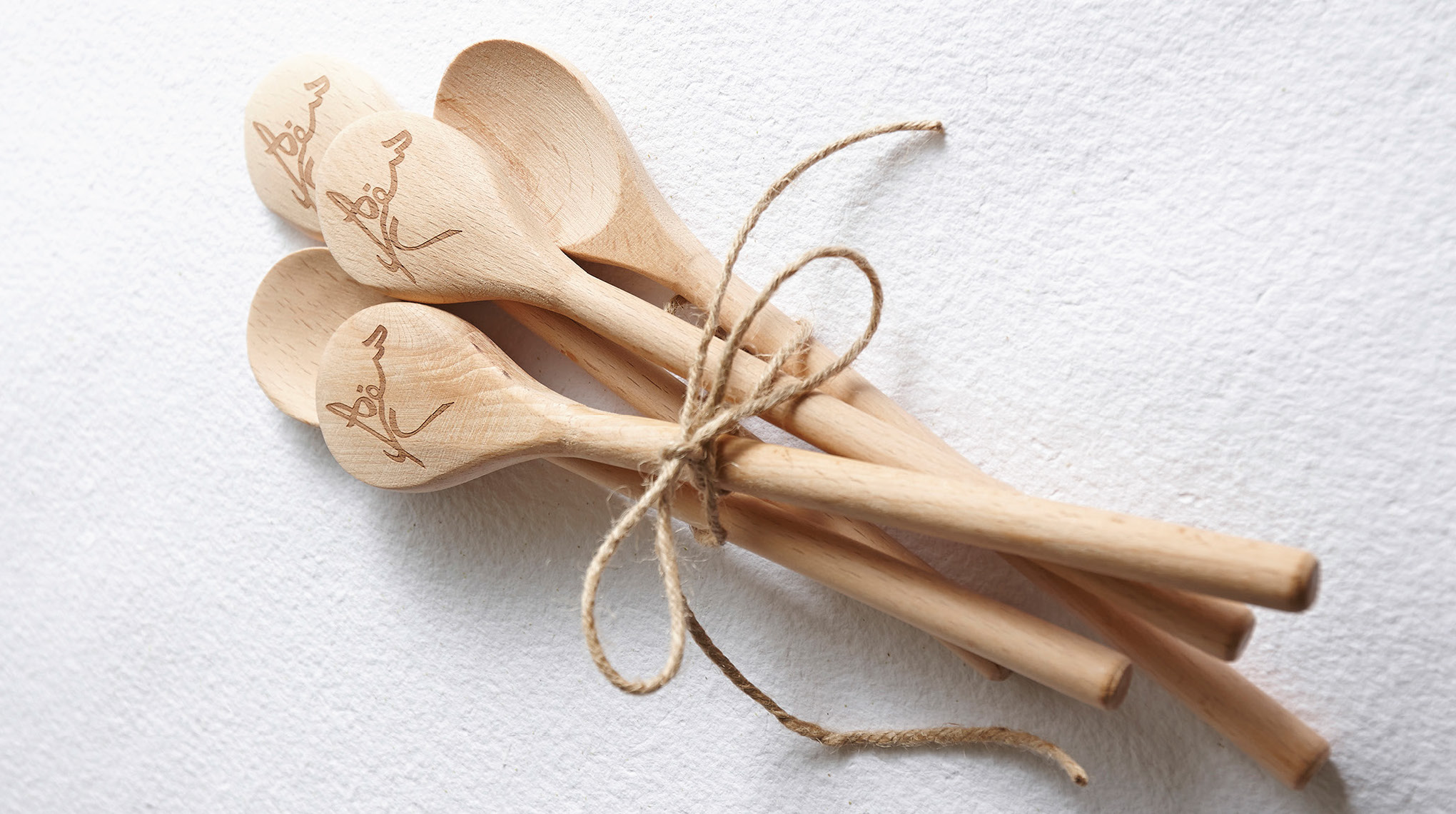 A bundle of wooden spoons with Sofreh logo