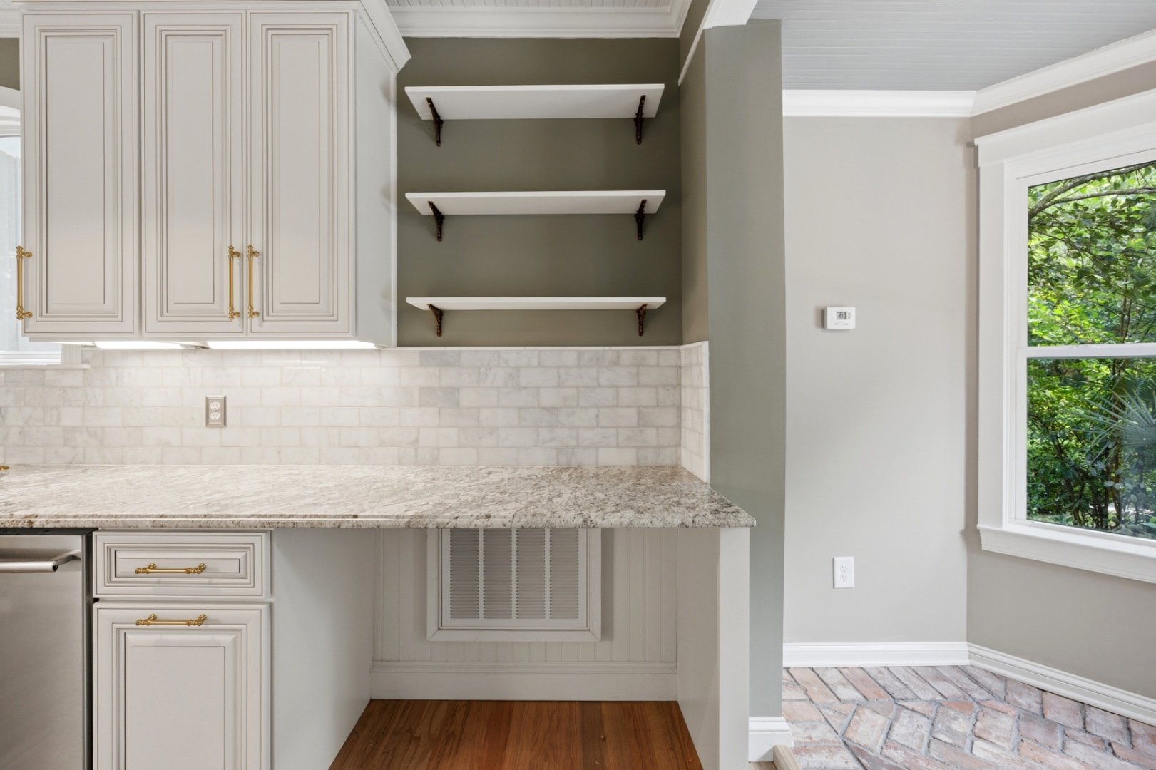 Custom open shelving built into a kitchen nook, framed by marble tile.