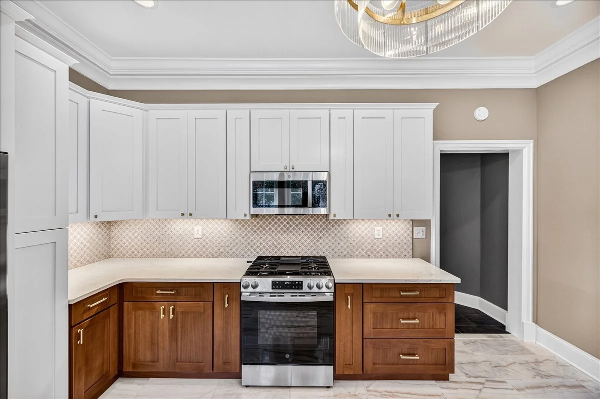 Two-tone custom cabinetry with quartz countertops and a diamond mosaic backsplash.