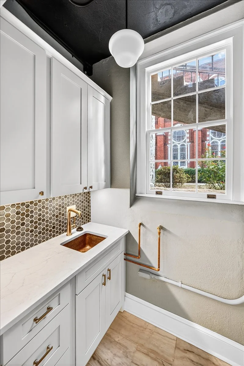 A custom butler's pantry with a copper farmhouse sink and hexagon tile backsplash.