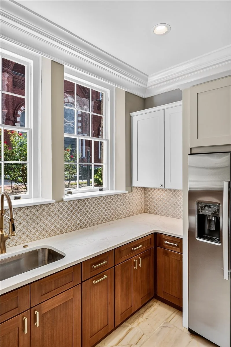 Wood-tone custom cabinetry with a built-in refrigerator surround and tile backsplash.