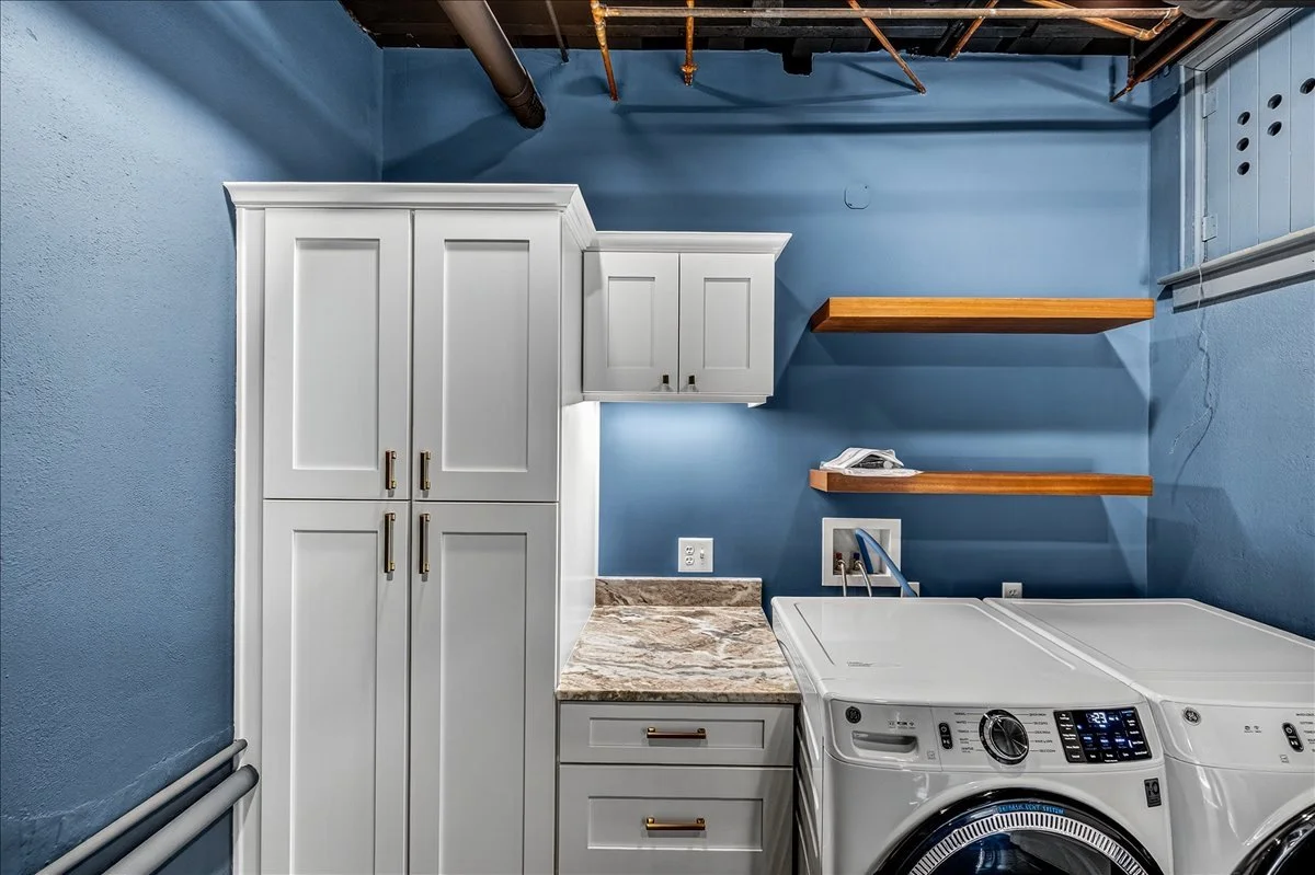Custom laundry room cabinetry with floating wood shelves and a built-in folding counter.