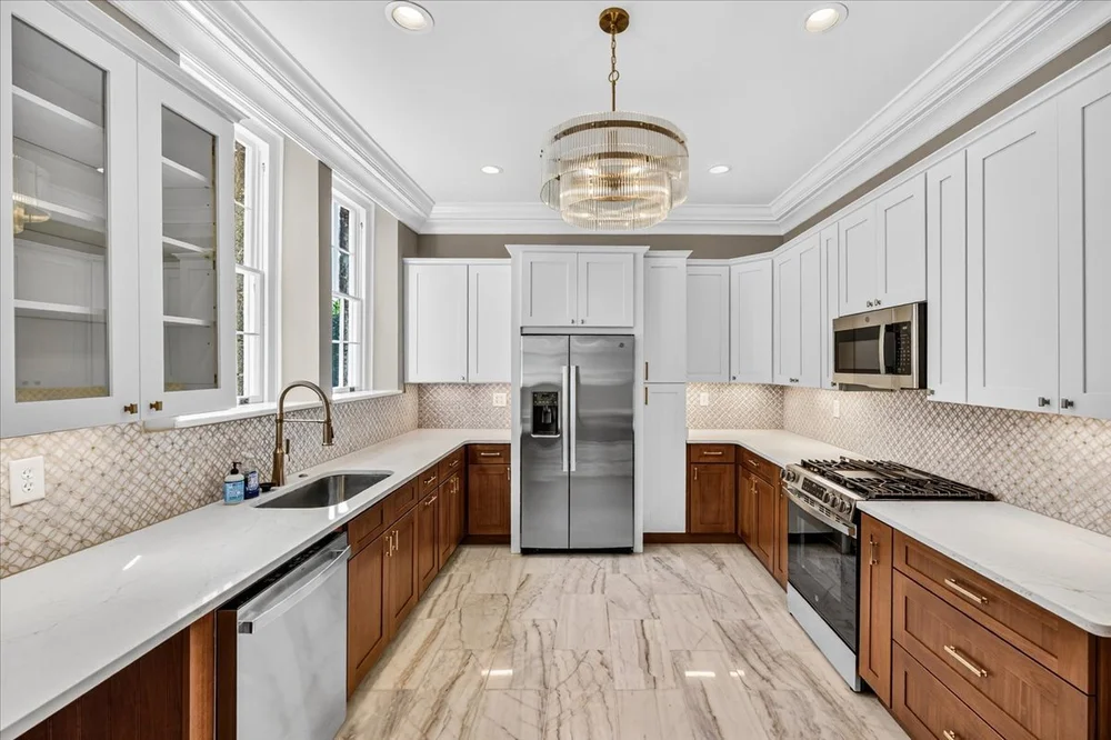 MCW kitchen with white upper cabinets, warm wood base cabinets and a window-side sink