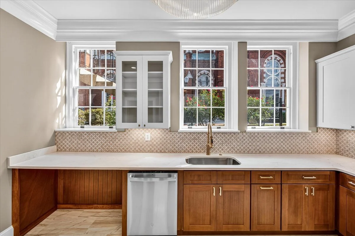 Kitchen sink wall with wood base cabinets and a glass-front upper cabinet