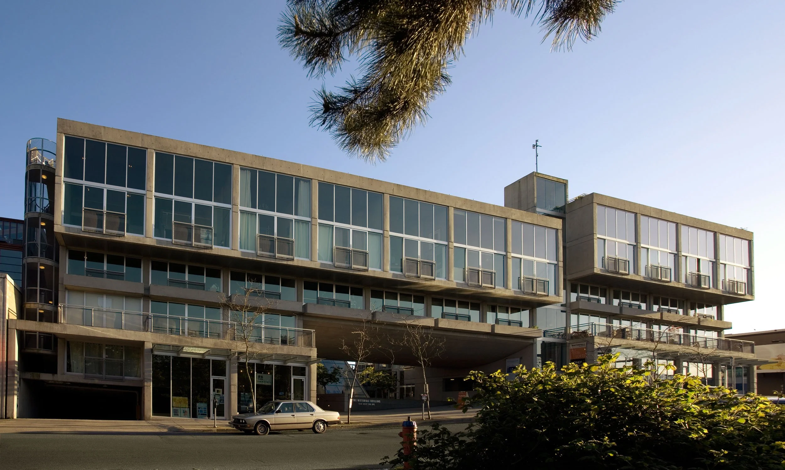 Vertical view of the Waterfall Building's concrete bridge and the falling water curtain at the entry.