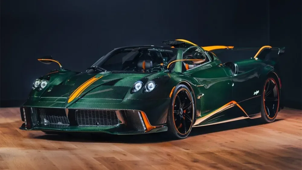 Green race car with orange accents and black wheels on a wooden floor.