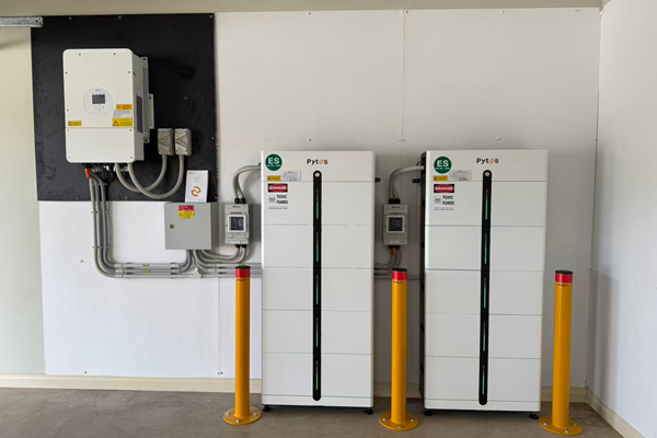 Industrial electrical equipment setup with control panels and safety barriers on white walls.